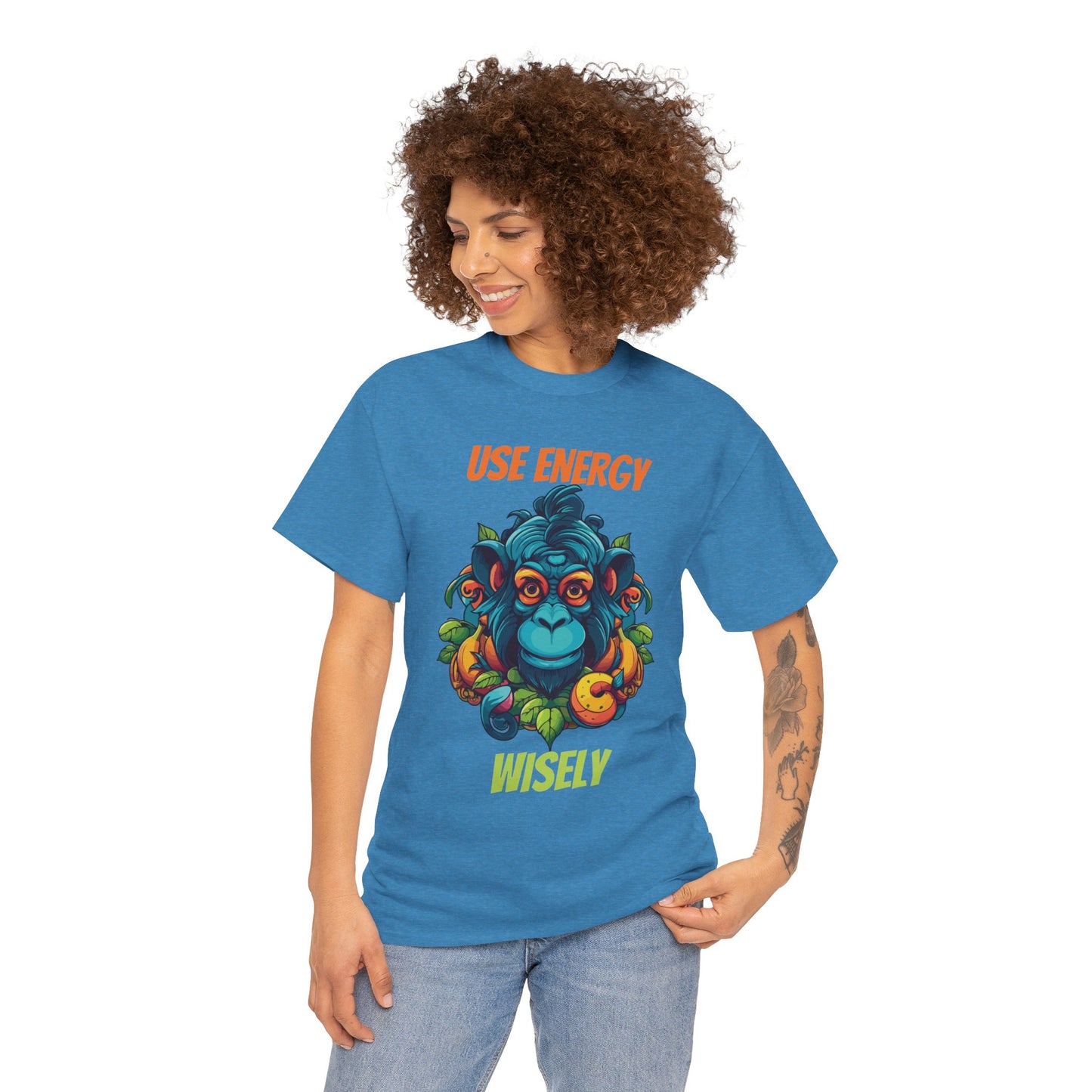 A person wearing a blue unisex heavy cotton tee with a graphic design that includes the text 'USE ENERGY' and an illustration of a monkey.